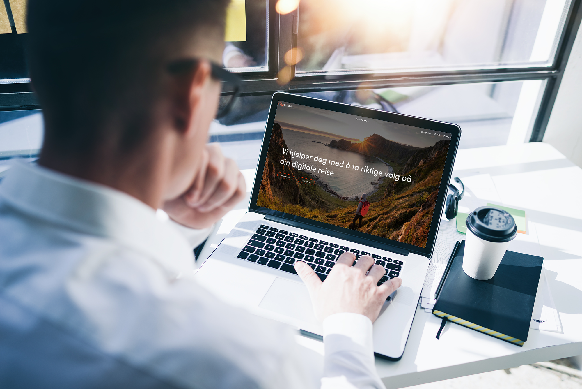 Man with laptop at desk looking at Crayon webpage